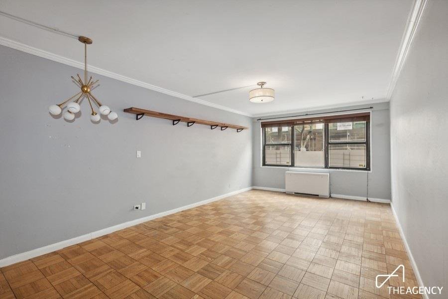Empty room with parquet flooring and a window at 200 E 27th Street 1-B