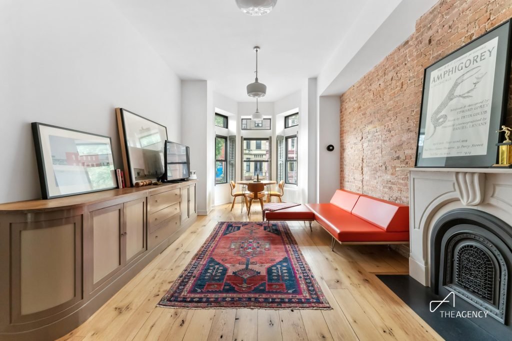 Long room with an exposed brick wall and a fireplace at 579 Jefferson Avenue 2